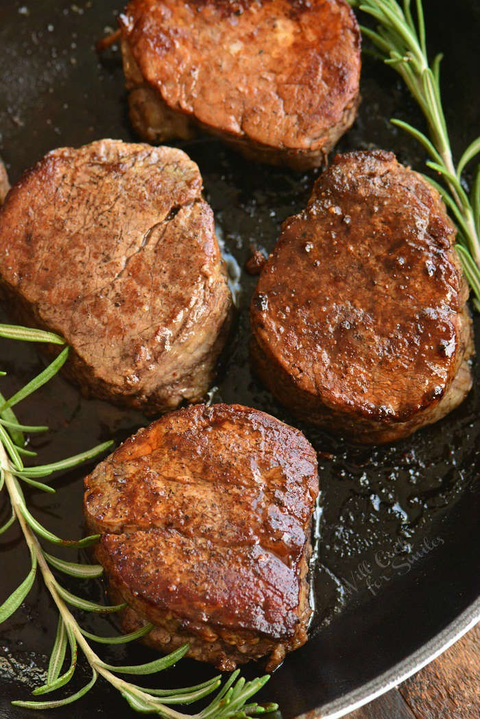 four filets in a cast iron skillet with rosemary sprigs.