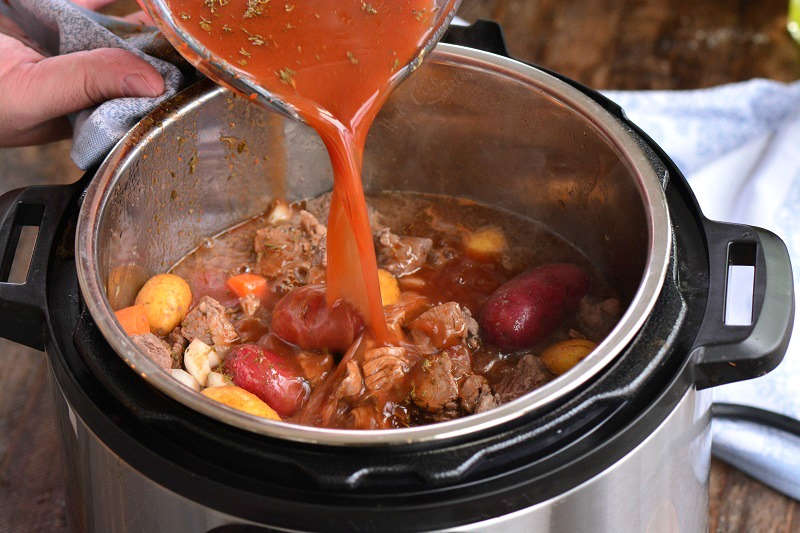 adding broth to the stew in the instant pot