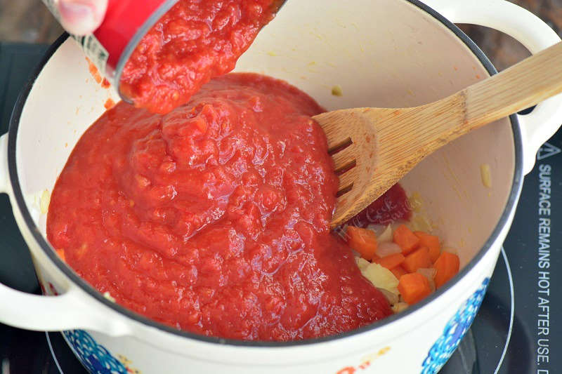 adding crushed tomatoes to the pot