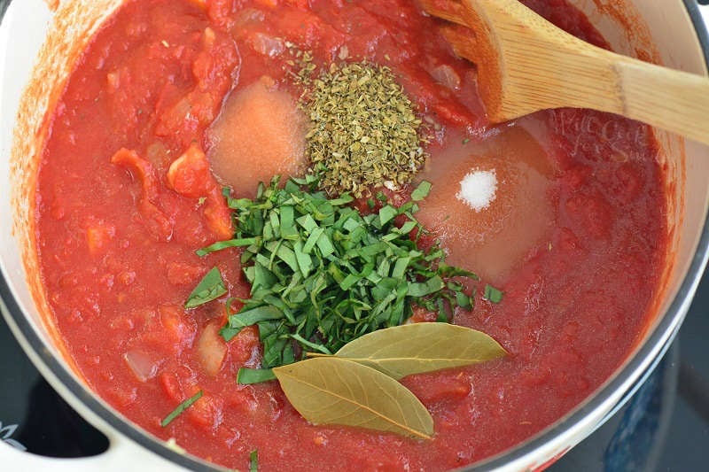 adding seasoning and herbs to the tomato mixture