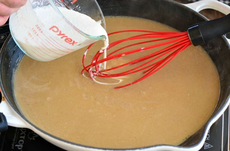 adding heavy cream to the gravy in a pan with a whisk 
