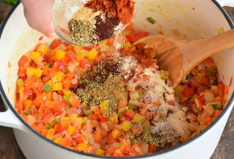 adding chili seasoning to the pot with vegetables.