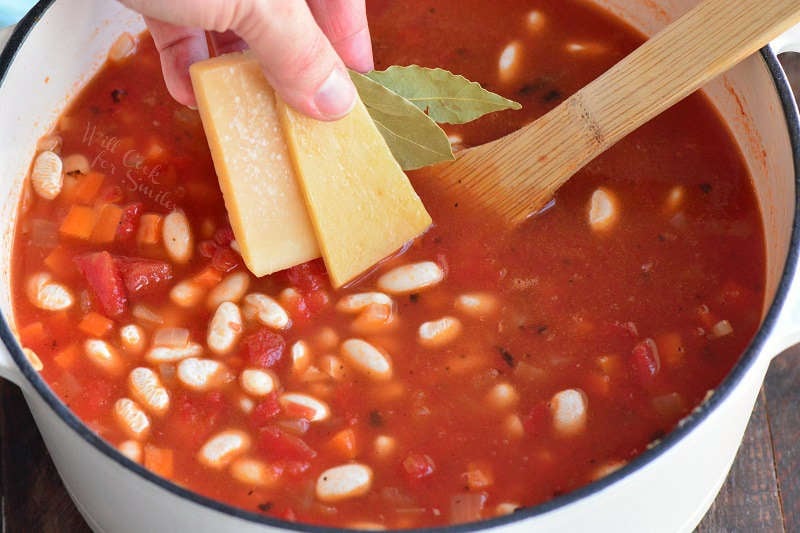 adding Parmesan and bay leaves to the pot 