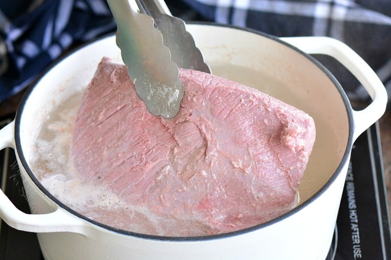 pulling corned beef out of the pot with water