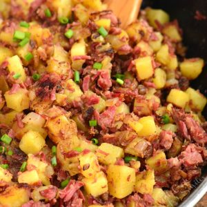 closeup of corned beef hash in skillet with spoon.