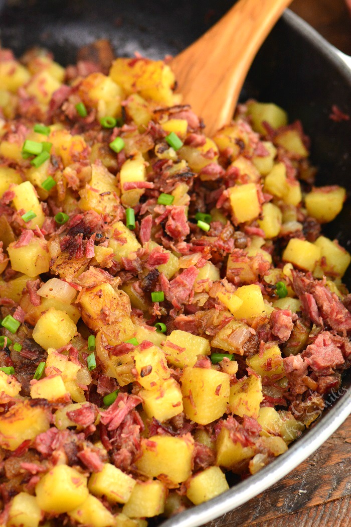 closeup of corned beef hash in skillet with spoon.