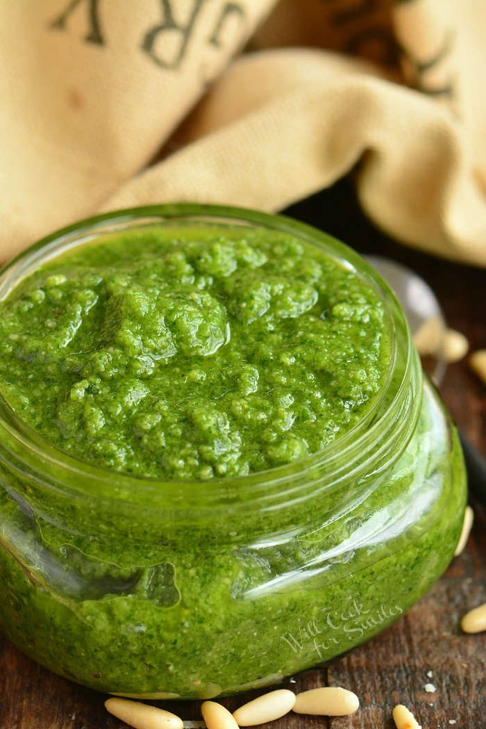 side view of a glass jar filled with basil pesto.