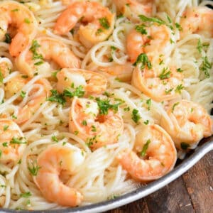 shrimp over spaghetti in a skillet with some parsley.