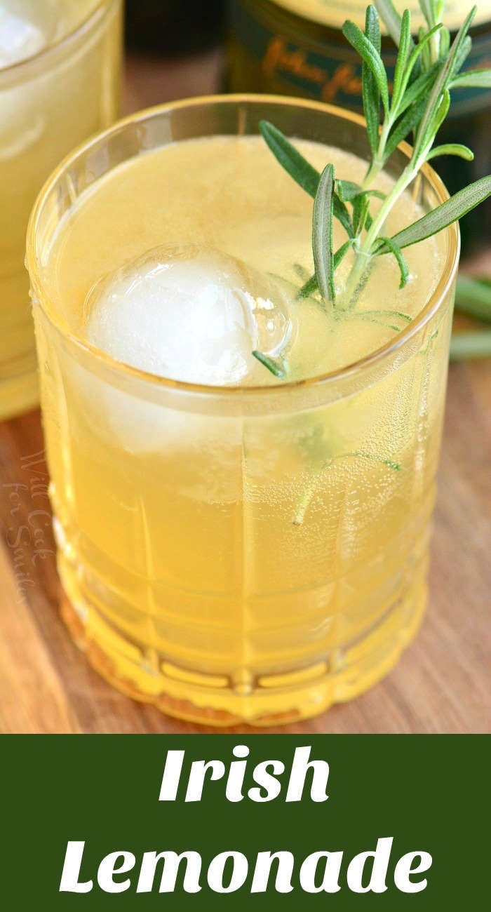 closeup of light yellow cocktail in a glass with rosemary.