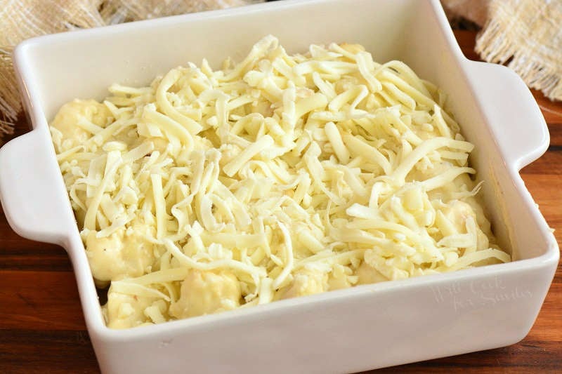 cheesy cauliflower in the baking pan topped with shredded cheese