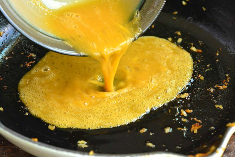pouring whisked eggs into the pan