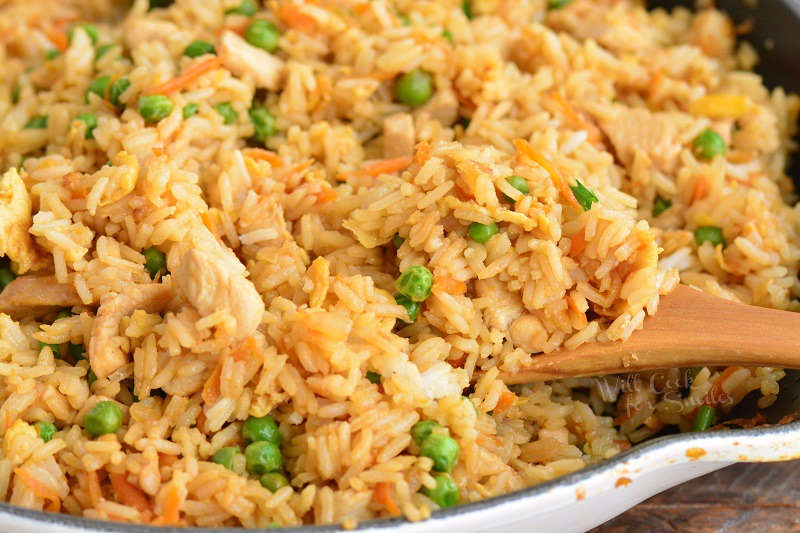 cooked chicken fried rice in the pan with wooden spoon scooping the rice