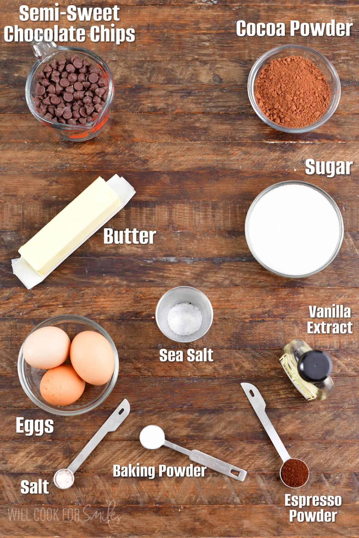 labeled ingredients to make flourless chocolate cake on a wooden board.