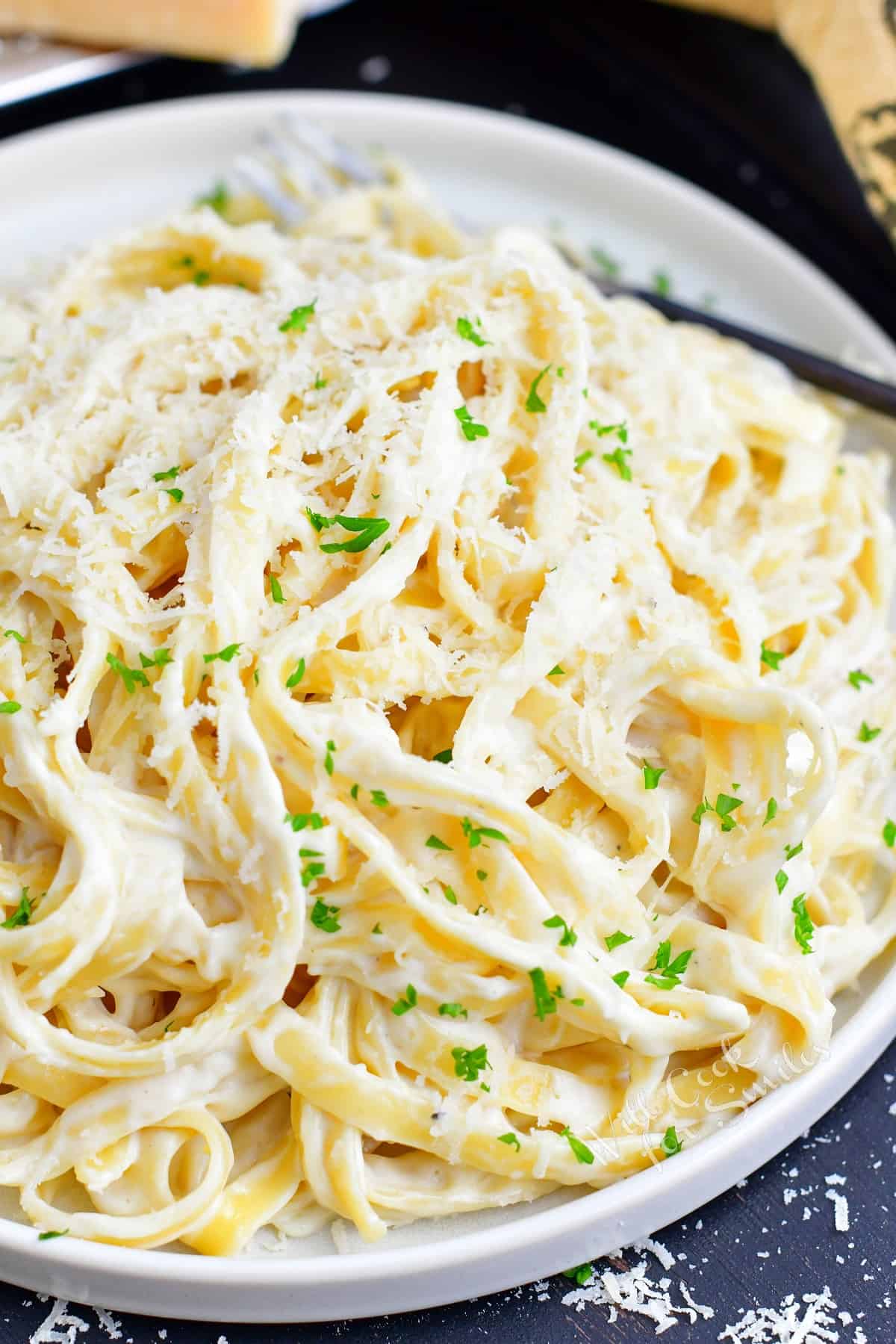 closeup of fettuccine Alfredo in a light plate with parsley.