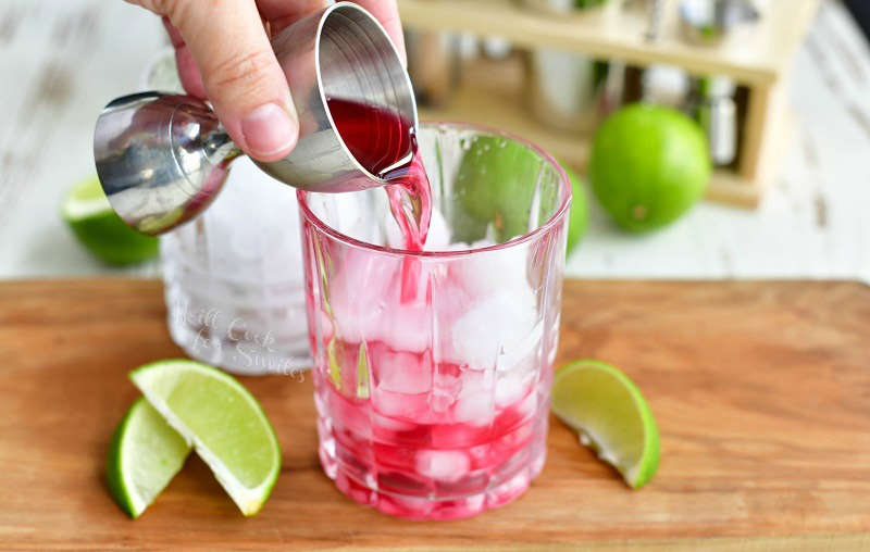 pouring cranberry juice into the glass with ice