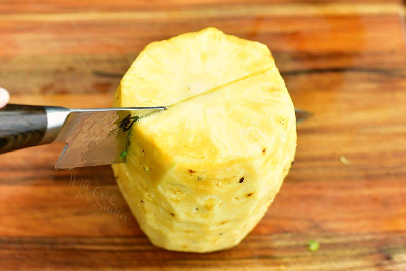slicing a whole pineapple without the skin in half