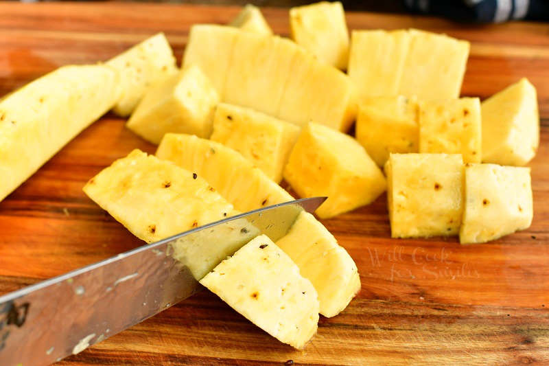 cutting pineapple quarter into chunk with a knife