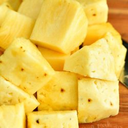 cut pineapple into chunks on a cutting board