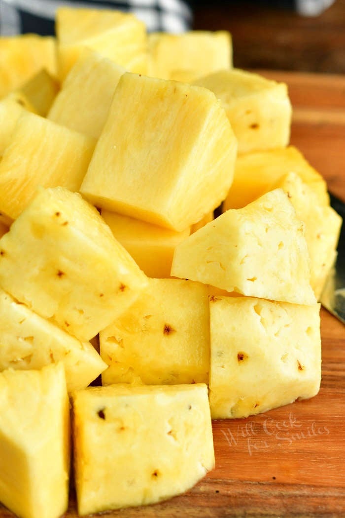 cut pineapple into chunks on a cutting board 