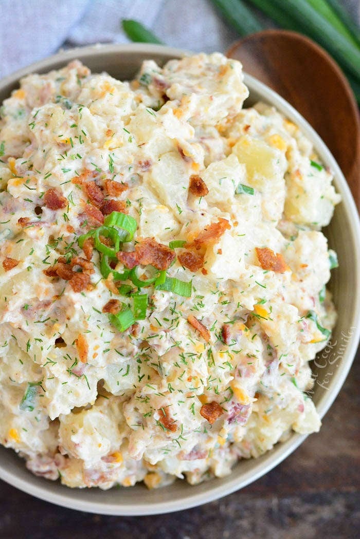 above view on ready potato salad in a bowl with green onion and bacon bits on top and spoon next to the bowl