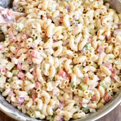 mixing macaroni salad in a metal mixing bowl