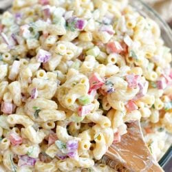scooping prepared macaroni salad with a wooden spoon