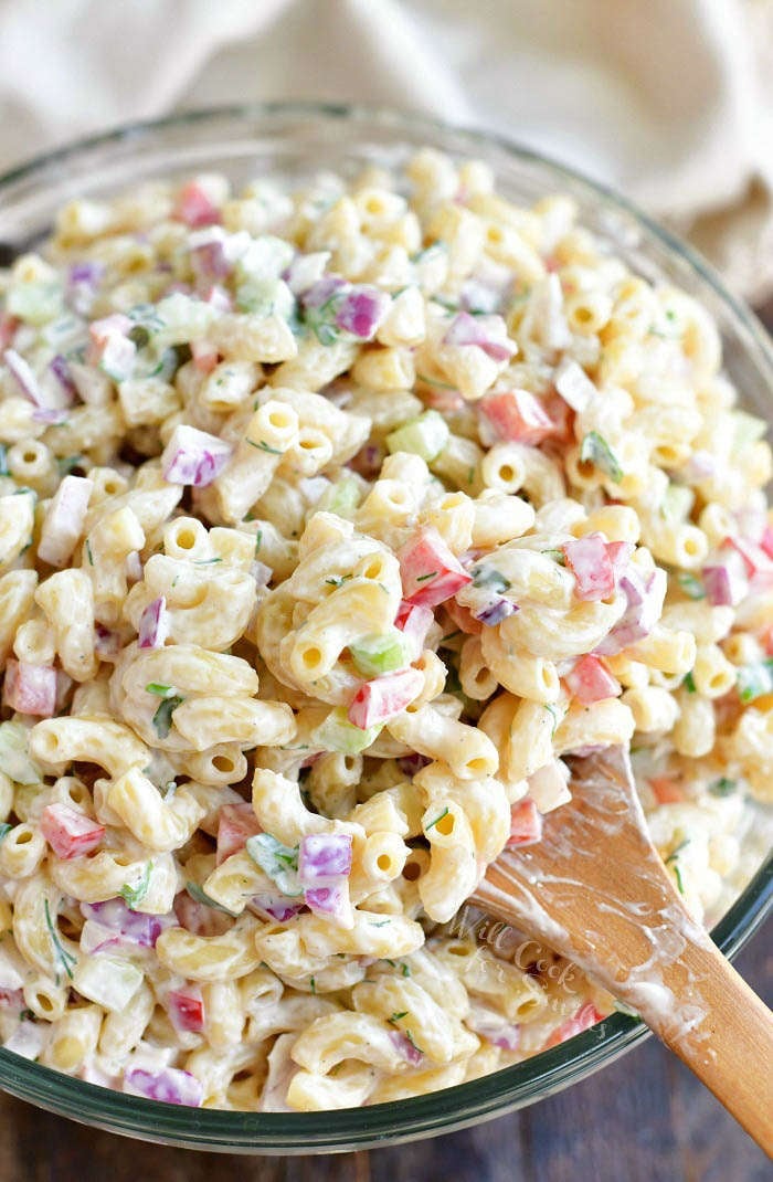 scooping prepared macaroni salad with a wooden spoon