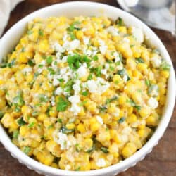 creamy Mexican corn salad in a white bowl topped with crumbled queso.
