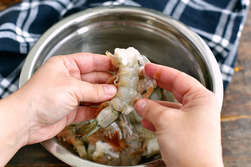 holding a shrimp and peeling off the shell