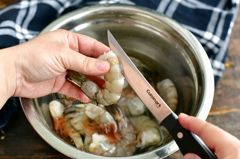 holding the shrimp and cutting through the top with a small knife