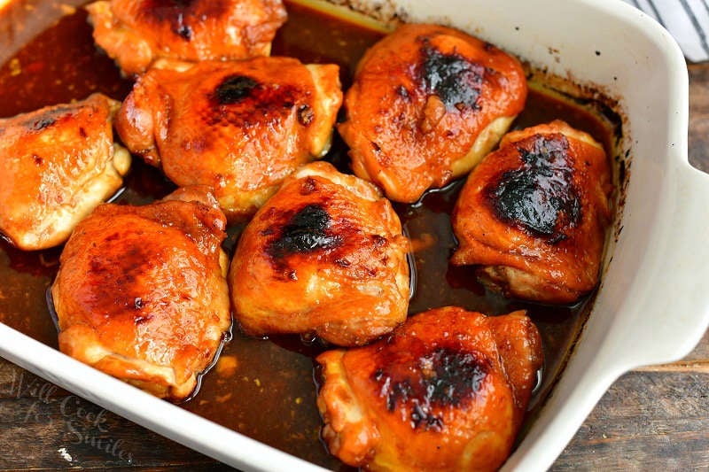 chicken thighs in dark brown asian sauce in a baking dish just out of the oven