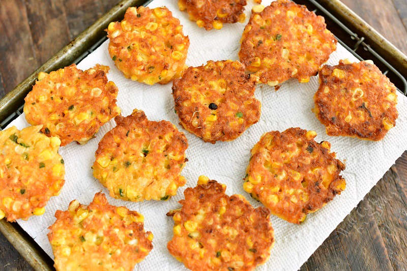 cooked fritters laid out side by side on paper towel on a wire rack