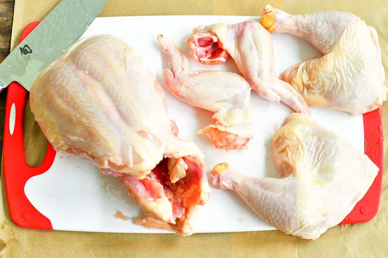 chicken legs and wings separated on the cutting board next to the breast and backbone still intact