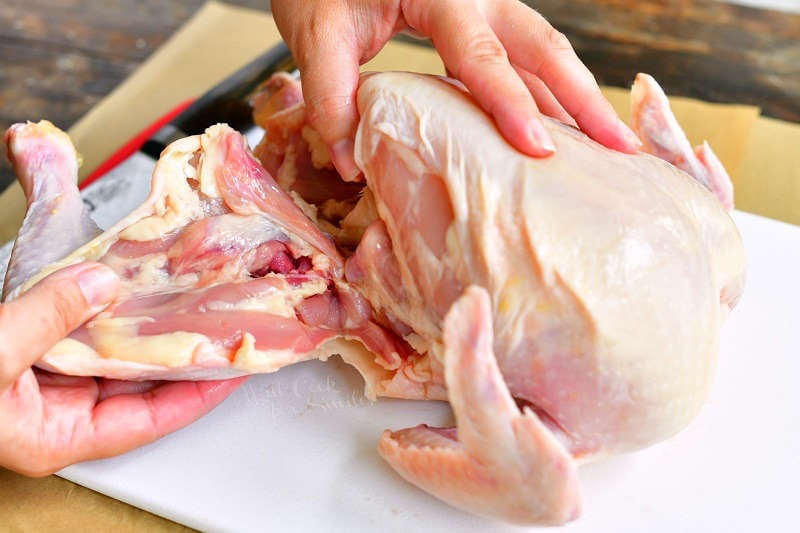 pulling the thigh off raw chicken to locate the joint