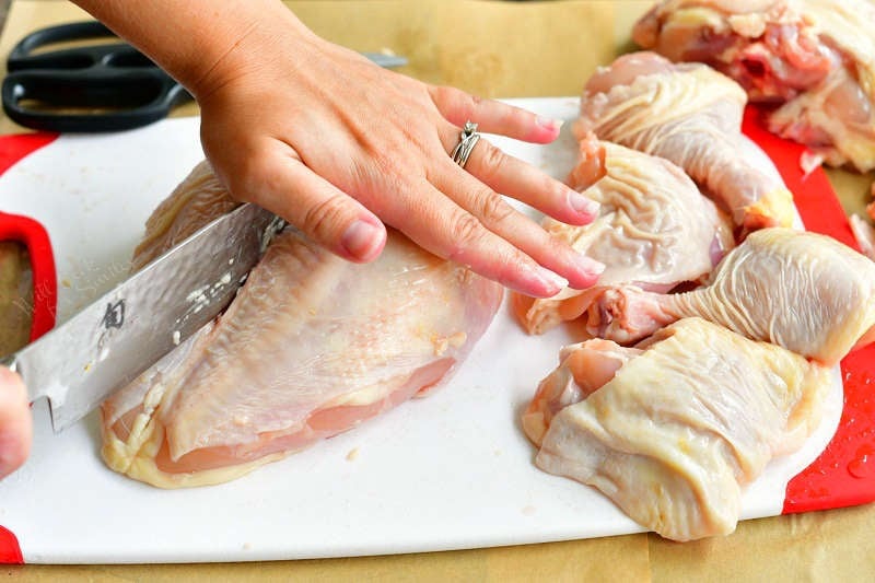 cutting down the middle of the chicken breast to separate it into two