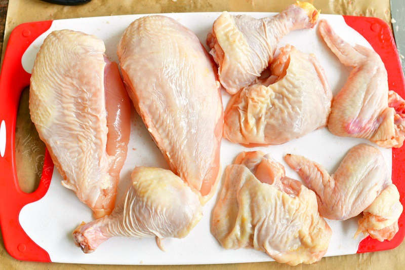 chicken broken down into 8 pieces on the cutting board