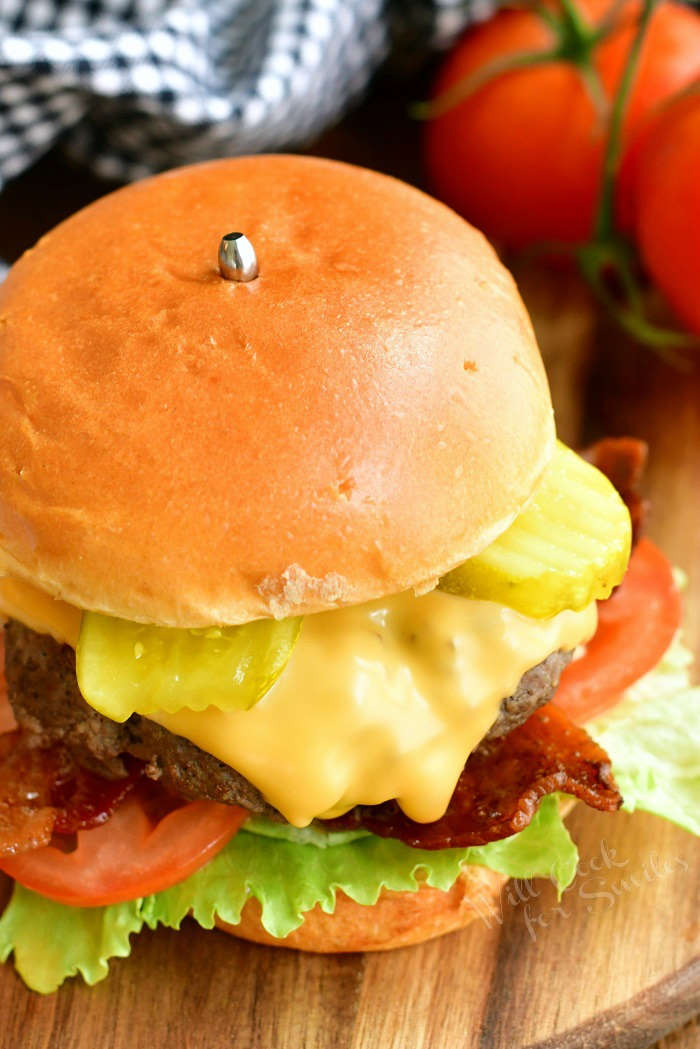 top view of cheeseburger on the board with tomatoes next to it and a towel