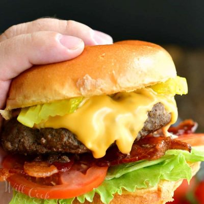 closeup of holding a cheeseburger with one hand