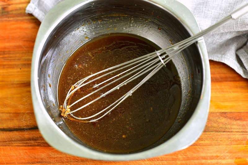 mixing bowl with marinade in it and a metal whisk