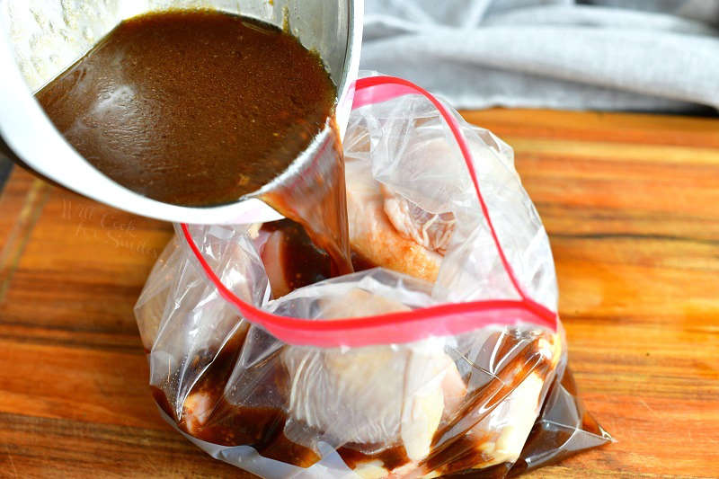 pouring marinade into a plastic bag with chicken already in it