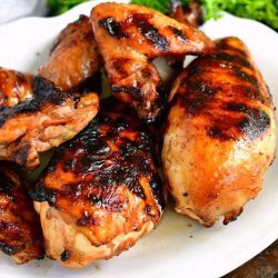 horizontal image of marinated grilled chicken pieces including breasts, wings, and thighs