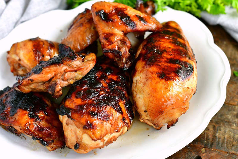 horizontal image of marinated grilled chicken pieces including breasts, wings, and thighs