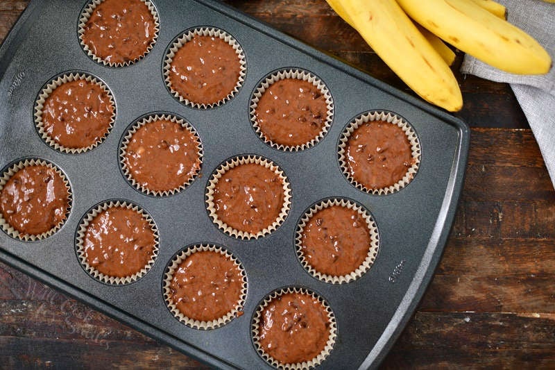 top view of muffin batter in a muffin pan with bunch of bananas next to it