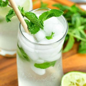 top view of mojito cocktail in a curvy glass with a paper straw and mint sprig