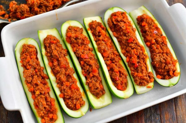zucchini halves paid side by side in a baking dish and filled with tomato beef mixture