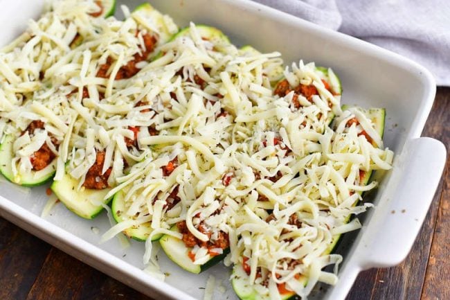 stuffed zucchini halves laid side by side filled with beef mixture and topped with shredded Mozzarella cheese