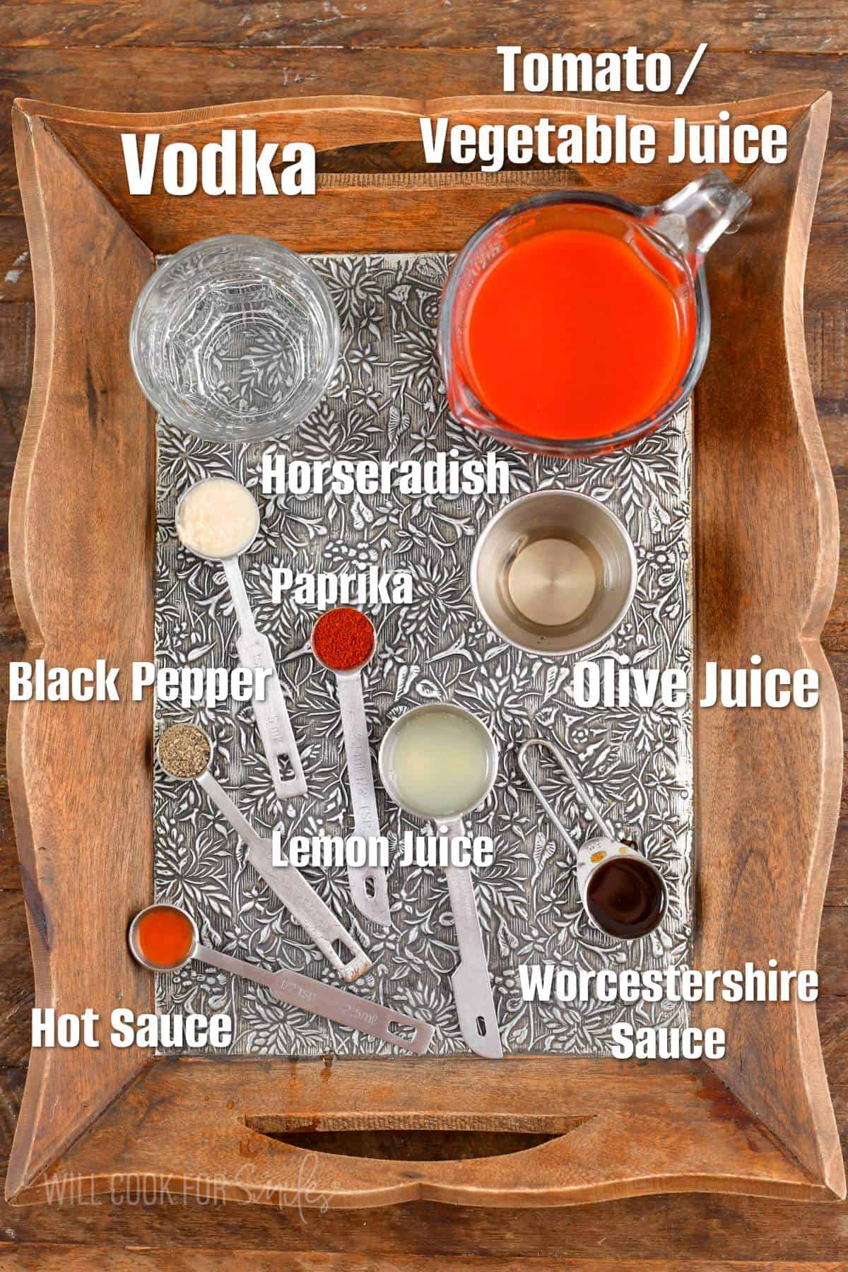 labeled ingredients for bloody Mary on a wooden and silver tray.
