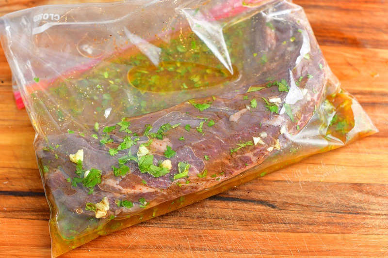 hanger steak marinating in a zip-top bag in a slightly orange marinade