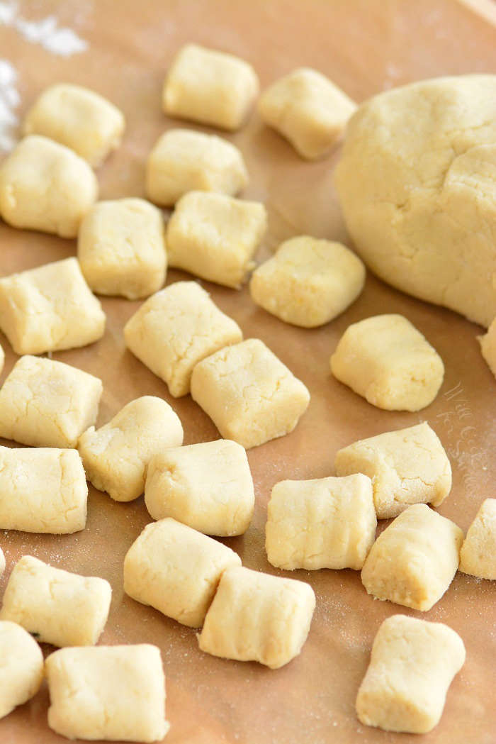 cut and rolled uncooked gnocchi spread out on a sheet on parchment paper