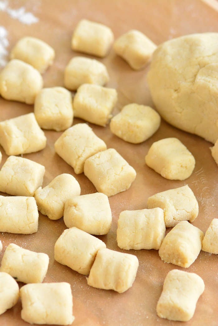 cut and rolled uncooked gnocchi spread out on a sheet on parchment paper